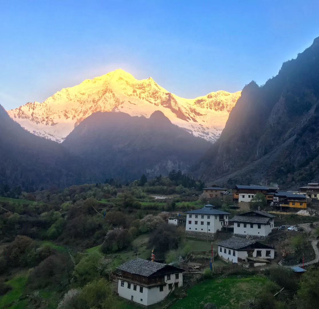 Des sommets enneigés dorés au lever du soleil au-dessus des maisons de Yubeng haut