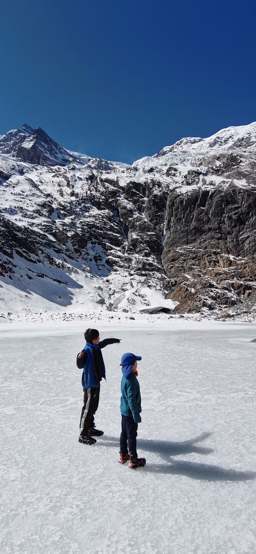 Deux enfants sur un lac gelé devant des sommets enneigés