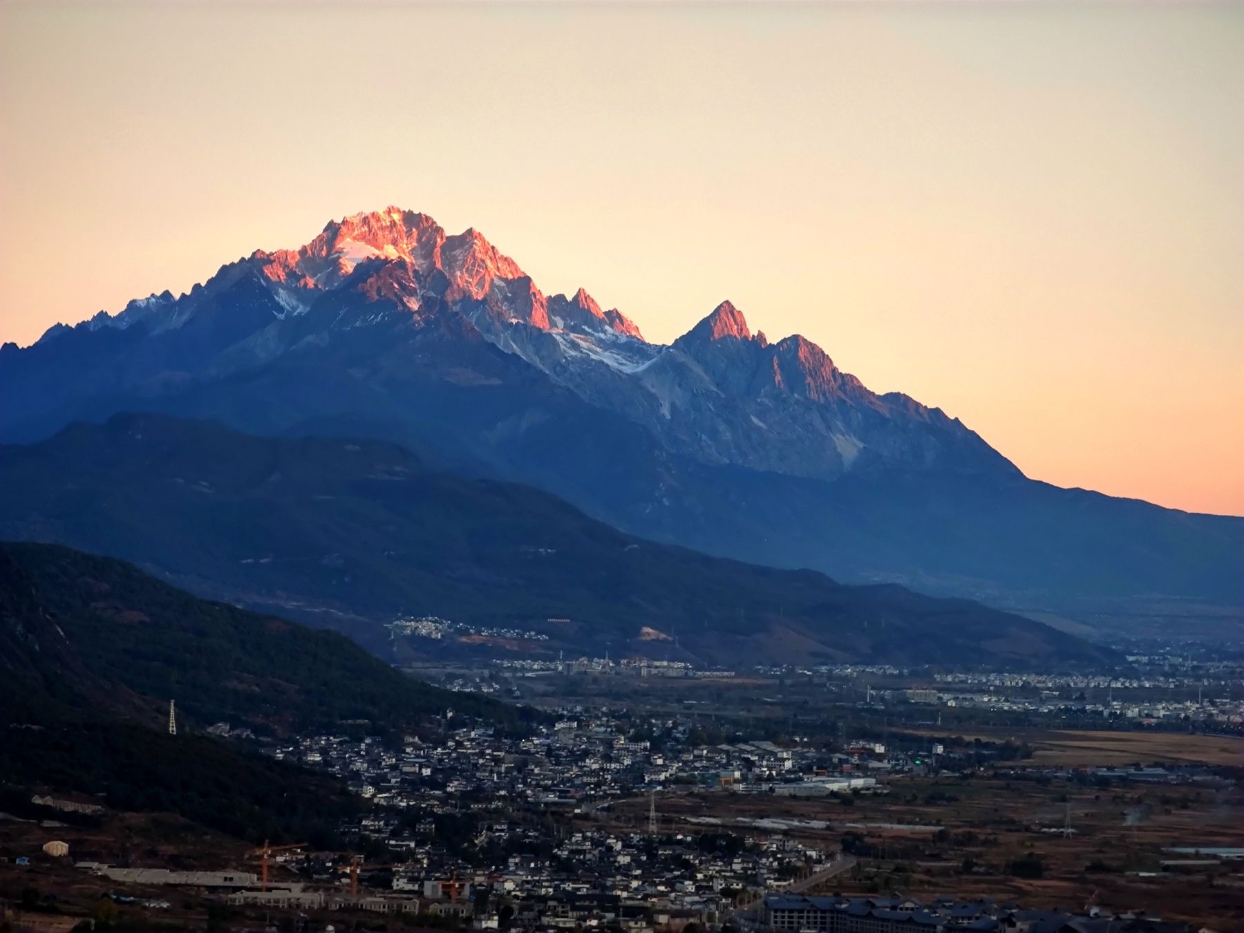 Le mont du Dragon de Jade éclairé en rose au-dessus de la ville de Lijiang