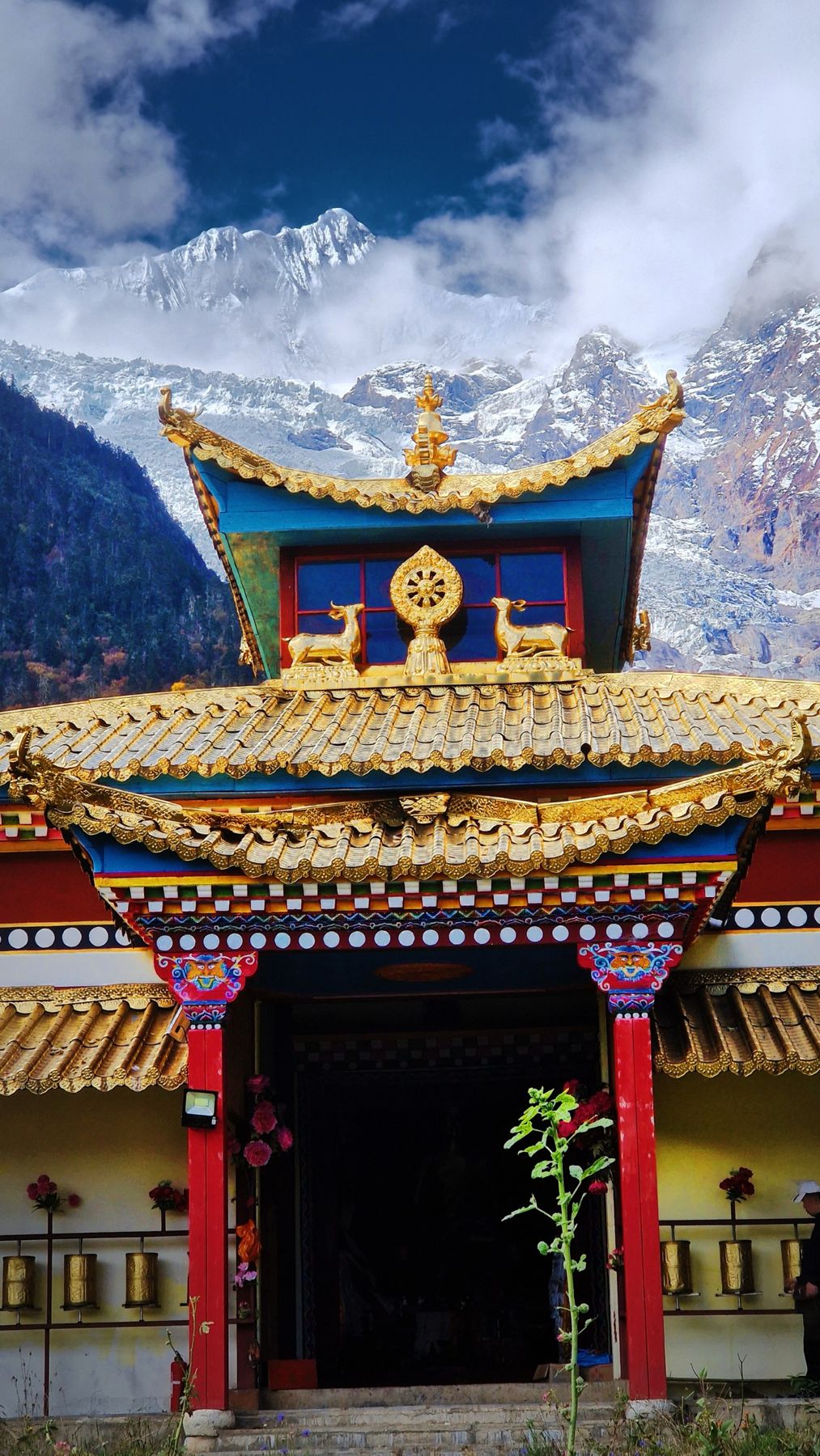 Le toit doré et les moulins à prière d’un temple tibétain sous les glaciers
