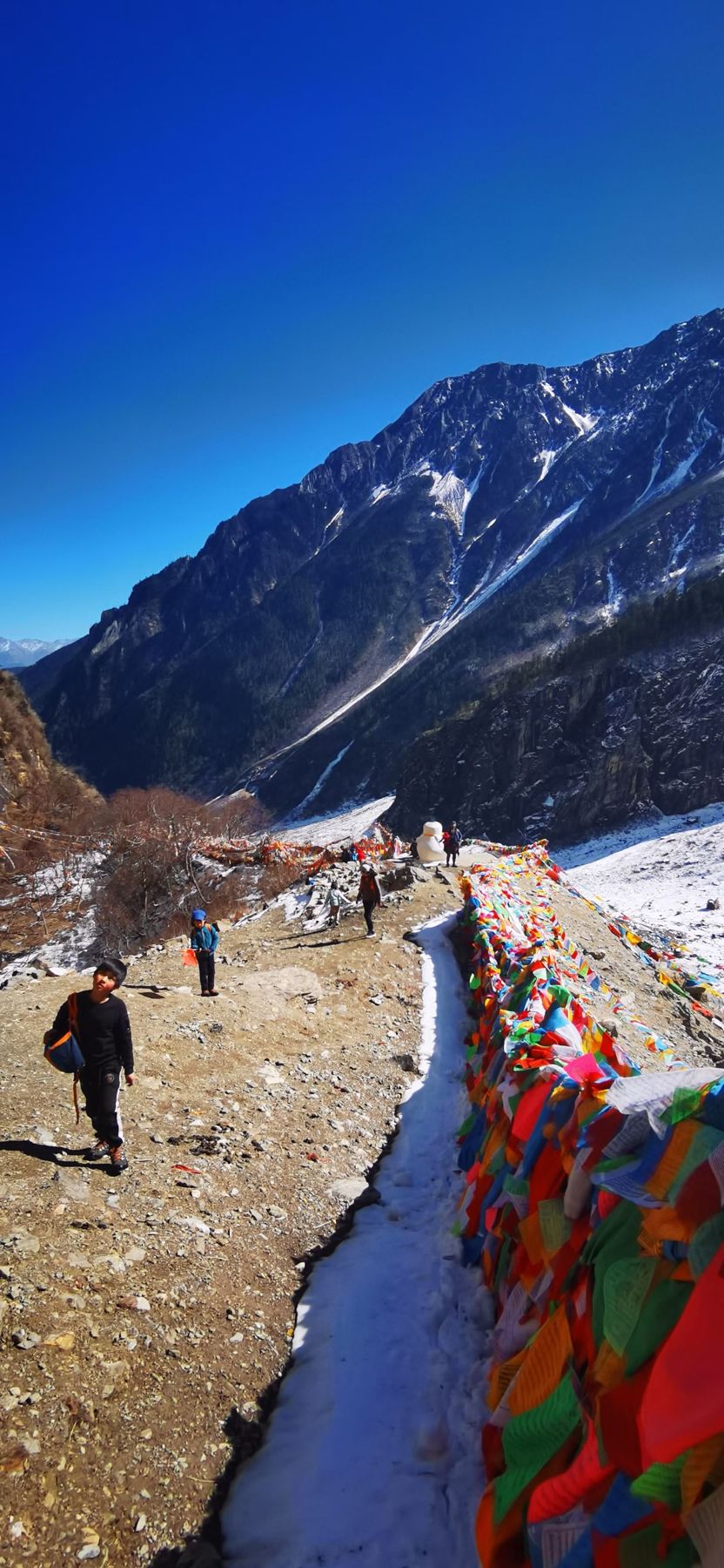 Des drapeaux de prière à côté d’un étroit canal d’eau sur un sentier de montagne