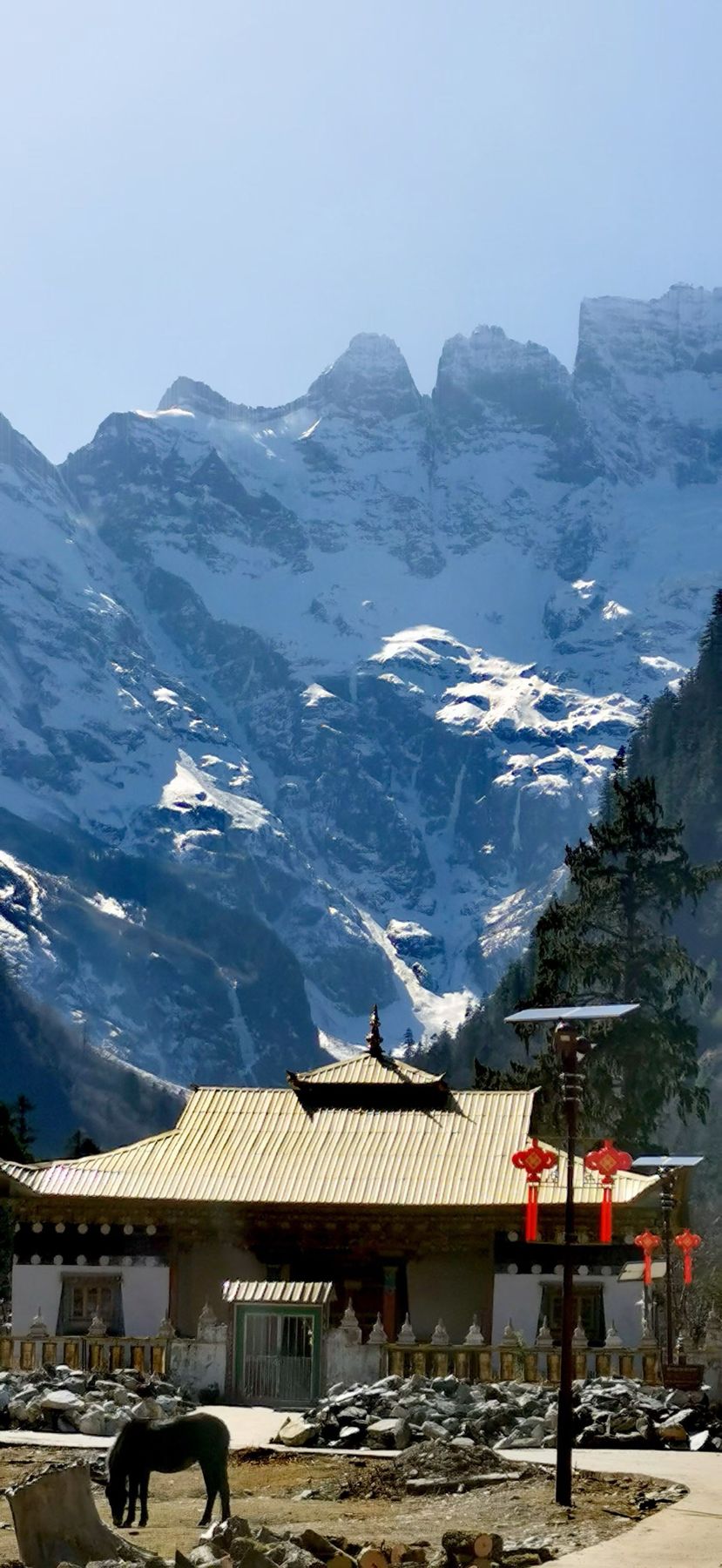 Un temple au toit doré avec un cheval et des sommets enneigés derrière